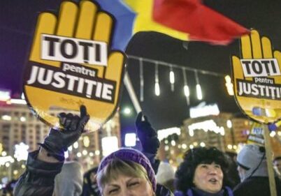 People hold cardboards reading "All for Justice" as they protest in front of the Romanian Government headquarters in Bucharest on December 10, 2017.                   
Around 7,000 Romanians took to the streets on Sunday in fresh protests at the left-wing government and what critics say are its attempts to go easy on corruption. / AFP PHOTO / Daniel MIHAILESCU